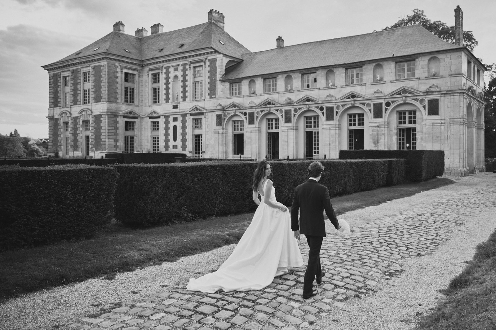 Les mariés remontant l'allée pavée vers le château