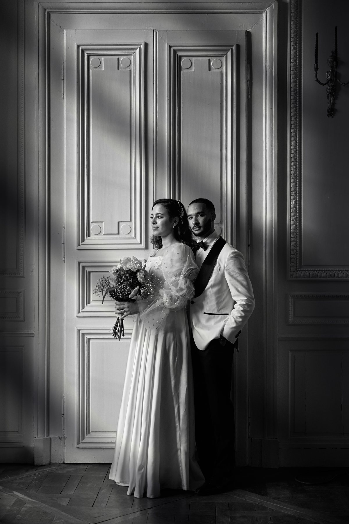 Les mari&eacute;s devant une grande porte, bouquet &agrave; la main