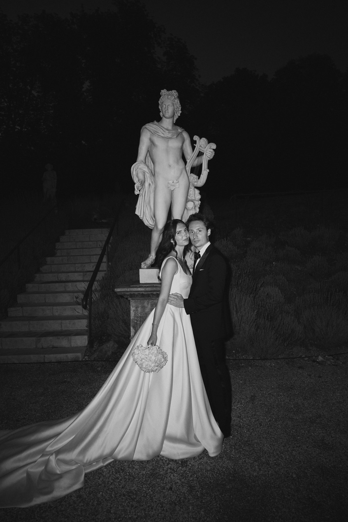 Les mari&eacute;s au pied d'une statue, la nuit, dans le parc du ch&acirc;teau