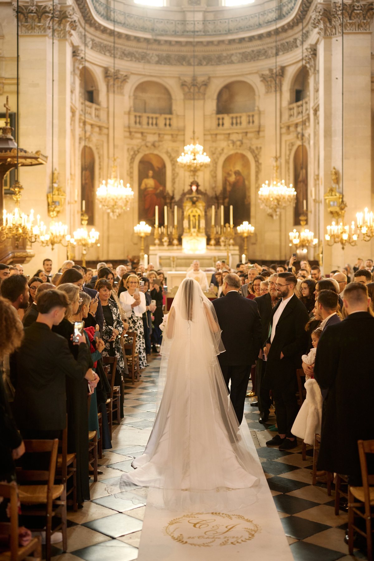 Entr&eacute;e de la mari&eacute;e dans l'&eacute;glise, voile d&eacute;ploy&eacute; dans l'all&eacute;e